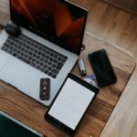 Laptop, tablet, and phone on a wooden desk.
