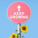 Pink sign with "keep growing" and sunflowers