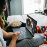 a couple of people sitting on a bed with a laptop
